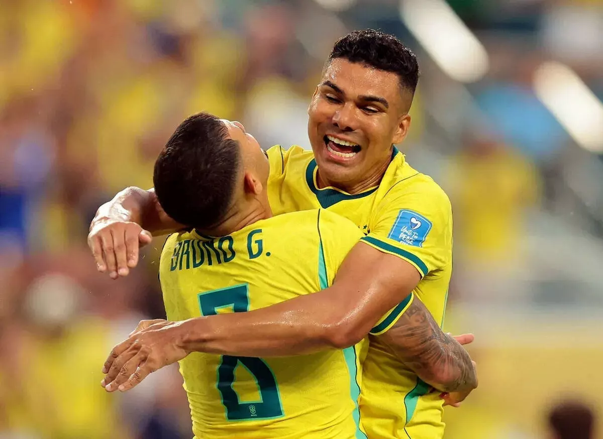 Brazil's Bruno Guimaraes celebrates with Casemiro after Matheus Cunha scores their third goal