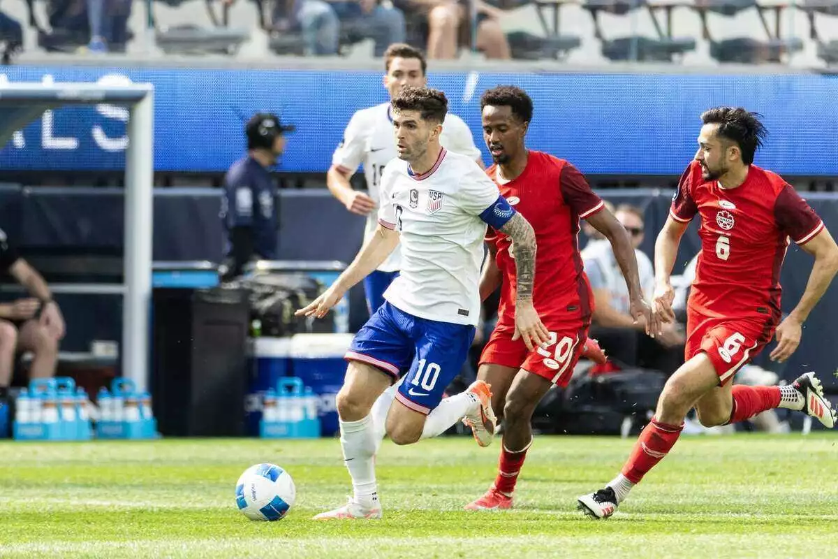 USA player Christian Pulisic dribbles past 2 Canadian defenders