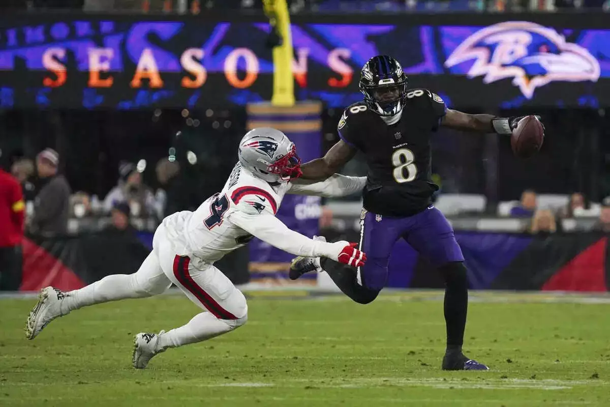 Ravens quarterback Lamar Jackson runs from Patriots defender